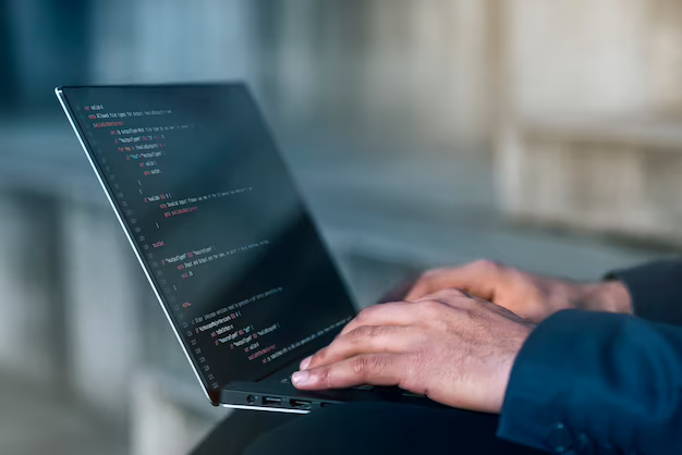 Hands writing program code on a laptop