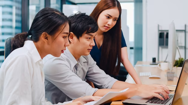 Three individuals focused on a laptop